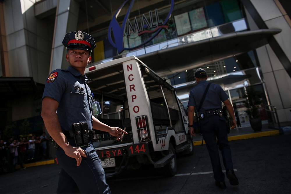 Policemen and emergency personnel take up positions outside a mall in Metro Manila, Philippines, where a gunman was said to have taken dozens of people hostage, March 2, 2020. 