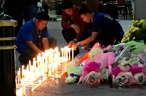 Staff at the Resorts World Hotel in Manila light candles and offer flowers in memory of colleagues and guests who died in a blaze after a gunman allegedly attacked the casino-hotel, June 2, 2017. 