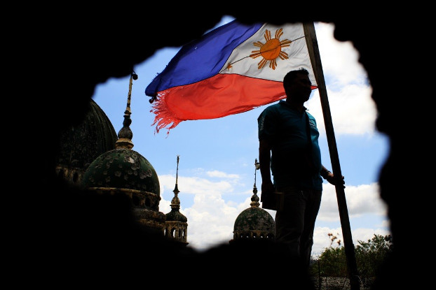 A tattered Philippine flag flutters in the wind near the pockmarked Grand Mosque in Marawi, May 16, 2018. (Richel V. Umel/BenarNews)
