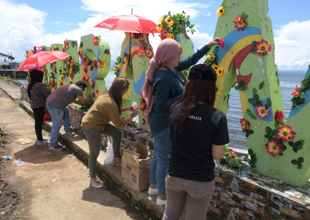 Members of an events-organizing group use flowers to decorate the bullet-riddled iconic sign “I love Marawi” to mark the second anniversary of the city’s liberation, Oct. 17, 2019. (Photo: Froilan Gallardo/BenarNews)
