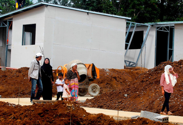 A family walks around a 32 acre property in the southern Philippine city of Marawi where about 1,700 housing units have been built for residents displaced, Nov. 23, 2017. (Mark Navales/BenarNews)