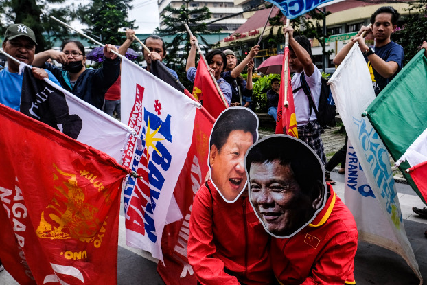 Members of the indigenous rights group Cordillera People’s Alliance carry flags pointed at their fellow demonstrators wearing Duterte and Xi masks during a protest rally in the northern Philippine city of Baguio, July 22, 2019. [Jojo Rinoza/BenarNews]