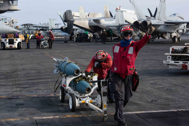 U.S. Navy men transfer bombs from a designated holding location to an aircraft on the flight deck of the U.S. aircraft carrier USS Ronald Reagan, near the disputed region of the South China Sea, Aug. 17, 2019. [Janweb B. Lagazo/U.S. Navy] 