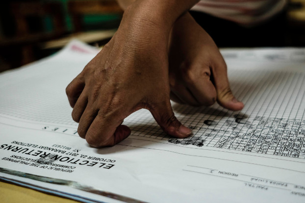 Election tellers and poll watchers affix their signatures and thumb marks on the official election returns for village polls in the northern Philippine city of Dagupan, May 14, 2018. [Karl Romano/BenarNews]