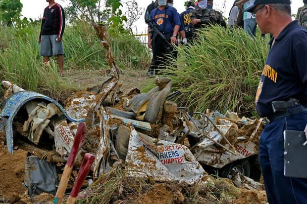 Policemen look at a crushed UNTV news vehicle in the hills of Ampatuan town in the southern Philippines, Nov. 23, 2009. [Nonoy Espina/BenarNews]