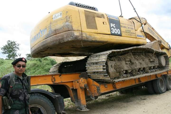A police officer guards the backhoe used to bury the victims and their vehicles in the hills of Ampatuan town in the southern Philippines, Nov. 23, 2009. [Nonoy Espina/BenarNews]