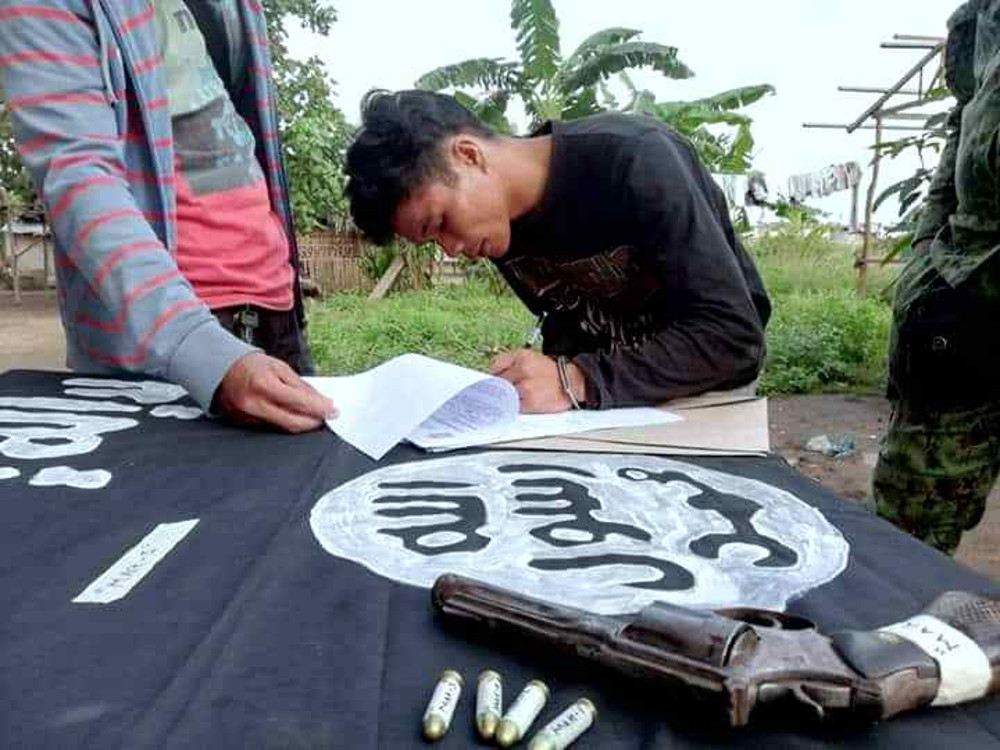 Suspected Filipino militant Jomar Maan signs police documents on a table draped with an Islamic State flag after his arrest in the southern Philippine city of General Santos, Sept. 17, 2019. (Photo: Joseph Jubelag/BenarNews)