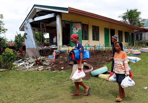 Displaced residents walk in front of a school building in the quake-hit Philippine village of Daig in Tulunan town, North Cotabato province, Oct. 30, 2019. [Jeoffrey Maitem/BenarNews]