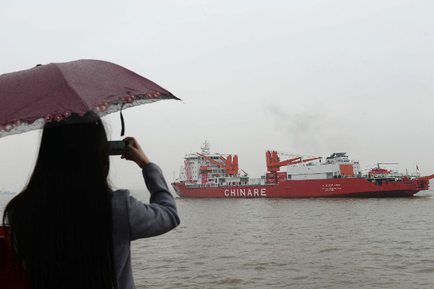 A woman takes a photo of Chinese research ship Xuelong as it departs a port in Shanghai in 2014. (AFP) 