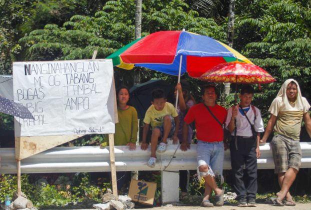Residents of Makilala, an earthquake-hit town in North Cotabato province in the southern Philippines, stand along a highway and hold signs asking commuters to give them food and water, Nov. 4, 2019. [Jeoffrey Maitem/BenarNews]