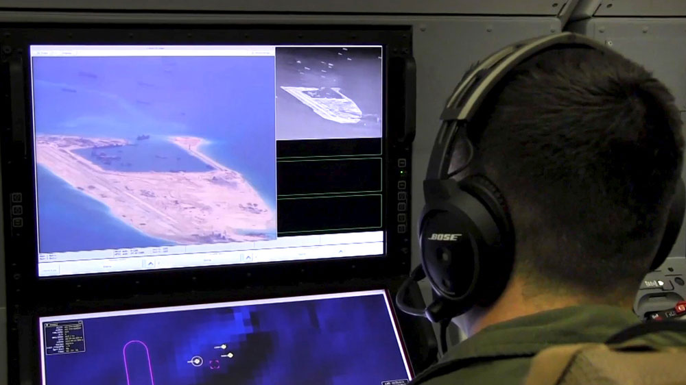 A U.S. Navy crewman aboard a P-8A Poseidon surveillance aircraft views a computer screen showing Chinese construction on the reclaimed land of Fiery Cross Reef in a still image from video provided by the United States Navy May 21, 2015. [Reuters] 