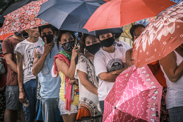 People try to protect themselves against exposure to COVID-19 as they wait for relief supplies in Manila, April 2, 2020. (Luis Liwanag/BenarNews)