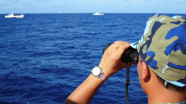 A Vietnamese Coast Guard ship crewman watches Chinese Coast Guard ships follow a Vietnamese ship near a South China Sea oil rig, July 2014. [Reuters]