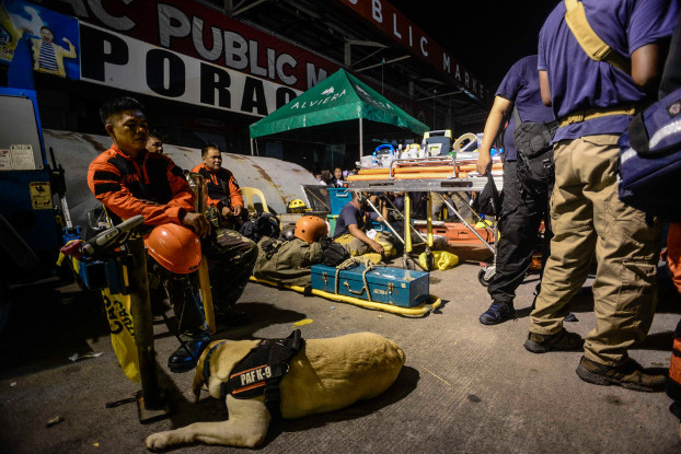 A search dog and his handler are on stand-by as rescuers search for survivors of the earthquake in Porac, April 22, 2019. [Jojo Rinoza/BenarNews]