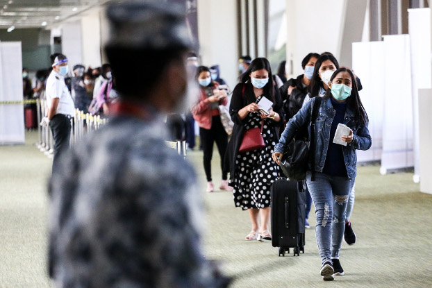 Filipino contract workers wearing protective masks arrive on a flight from Hong Kong at Ninoy Aquino International Airport in Manila, May 13, 2020. [Basilio Sepe/BenarNews]