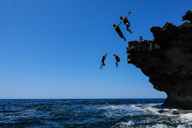 Tourists jump from a cliff at a beach in Bani municipality, Pangasinan province, Feb. 29, 2020.  