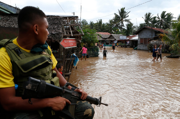 Locals in Salvador town, in Lanao del Norte province, wade through a flood left behind by rains from Tropical Storm Tembin, Dec. 23, 2017. 