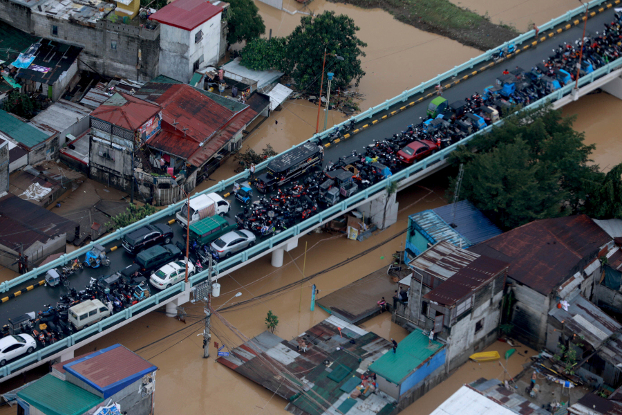 Vehicles and people stay on a bridge in Metro Manila to avoid floodwaters brought by Typhoon Vamco as others wait on rooftops to be rescued, Nov. 12, 2020. (Ace Morandante/Malacanang Presidential Photographers Division via AP)
