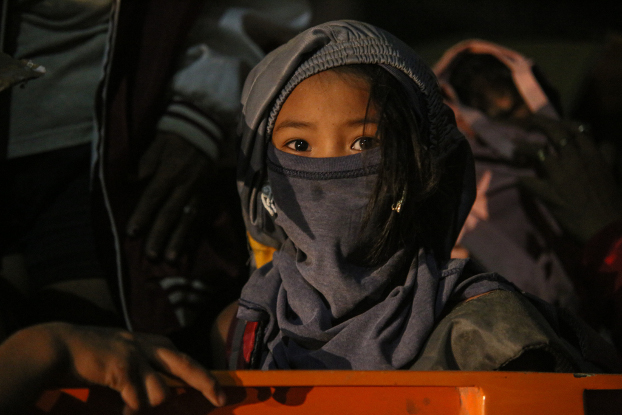 A young girl covers her head and face as her family evacuates from the danger zone near the Taal Volcano, Jan. 12, 2020. [Jojo Riñoza/BenarNews]