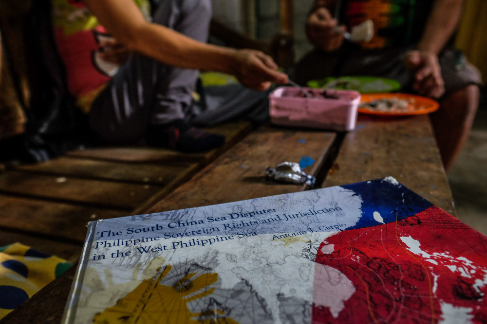 A book about an international court case in a territorial dispute over Scarborough Shoal sits on a bench in Johnny Sonny Geruela’s home as he and his wife share a meal, Sept. 6, 2019. [Jojo Rinoza/BenarNews]