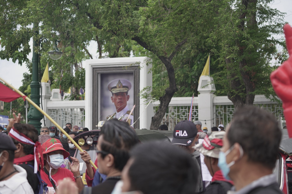 Anti-government protesters walk past a portrait of King Maha Vajiralongkorn in a Bangkok street, Sept. 19, 2020. [Nontarat Phaicharoen/BenarNews]