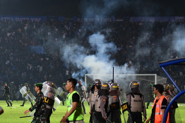 Foto yang diambil pada 1 Oktober 2022 ini menunjukkan gas air mata dilepaskan oleh polisi ke kerumunan orang di tribun setelah pertandingan sepak bola antara Arema FC dan Persebaya yang berakhir rusuh di stadion Kanjuruhan di Malang, Jawa Timur. Federasi Sepak Bola Internasional (FIFA) melarang penggunaan gas air mata di dalam stadion. [AFP]