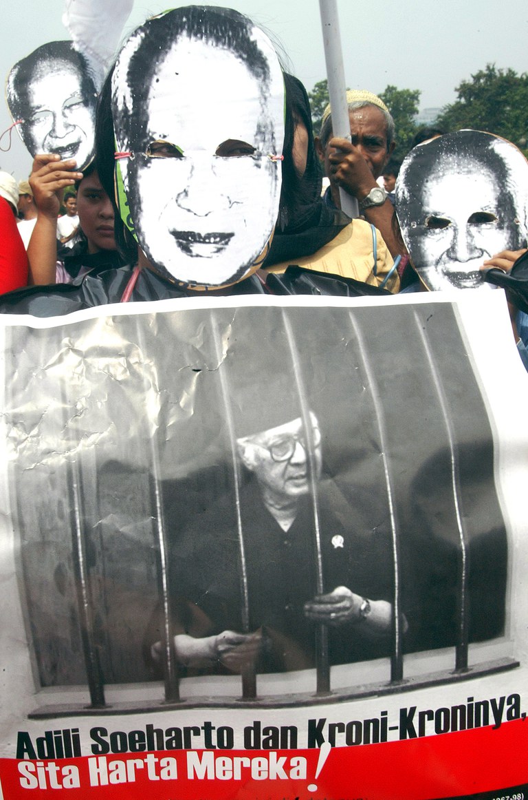 Para pengunjuk rasa mengenakan topeng bergambar mantan Presiden Suharto dan memegang poster dalam demonstrasi menentang mantan pemimpin otoriter tersebut di depan istana presiden di Jakarta, 21 Mei 2006. [Dadang Tri/Reuters]