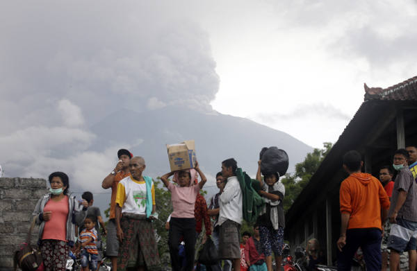 Sejumlah warga di Karangasem, Bali, mengungsi seiring dengan meletusnya Gunung Agung, terlihat di latar belakang, pada 26 November 2017. 