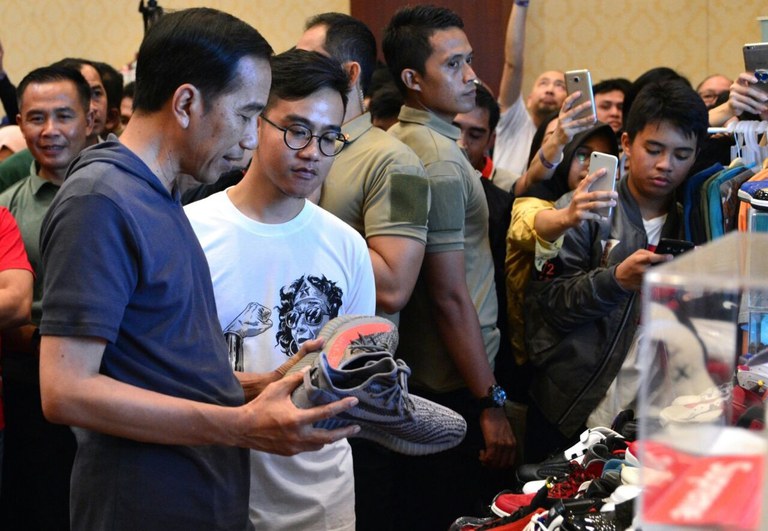 Presiden Joko Widodo (kiri) dan putra sulungnya yang kini menjadi Wakil Presiden terpilih, Gibran Rakabuming Raka, melihat sepatu di sebuah acara di Senayan City, Jakarta, 3 Maret 2018. [Courtesy Istana Kepresidenan Indonesia]