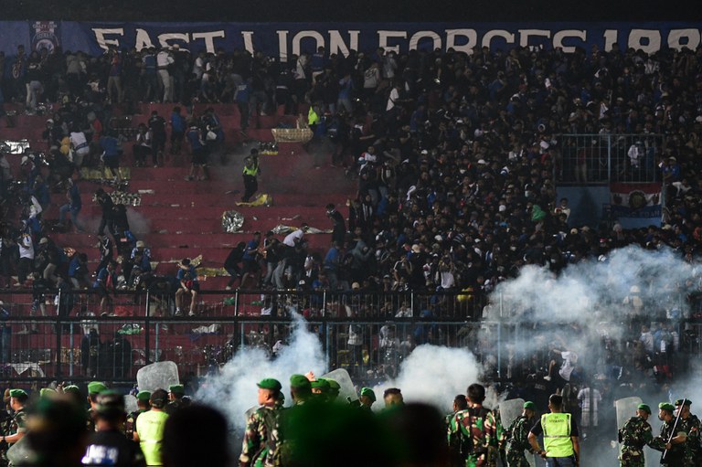 Foto yang diambil pada 1 Oktober 2022 ini menunjukkan kekacauan yang terjadi setelah para petugas menembakkan gas air mata ke arah para suporter tim Arema FC yang melakukan kerusuhan pasca kekalahan tim mereka atas tim Persebaya Surabaya di Stadion Kanjuruhan Malang, Jawa Timur. Setidaknya 125 orang tewas dalam tragedi yang tercatat sebagai salah satu bencana terburuk persepakbolaan di dunia. [STR/AFP]