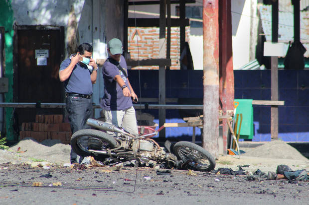 Penyidik polisi memeriksa sepeda motor yang rusak yang digunakan oleh pelaku bom bunuh diri menyusul serangan di kompleks kantor polisi Poso, di Sulawesi Tengah, 3 Juni 2013. [AFP]