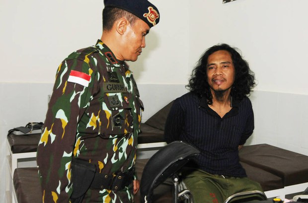 Seorang polisi menjaga tersangka militan MIT Muhammad Basri (kanan) di sebuah rumah sakit militer di Poso, Sulawesi Tengah14 September 2016. [Keisyah Aprilia/BenarNews]