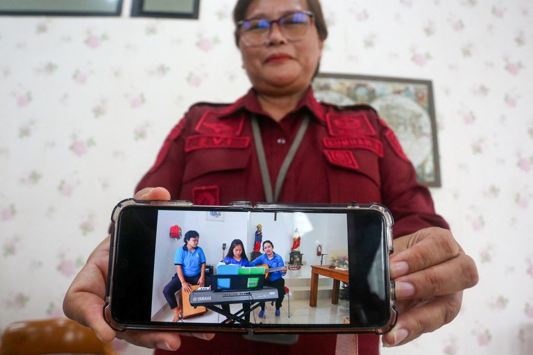 Evi Loliancy, kepala Lembaga Pemasyarakatan Wanita Kelas IIB di Wonosari, mengangkat telepon genggam yang menunjukkan foto terbaru narapidana hukuman mati Filipina Mary Jane Veloso (terlihat di tengah foto) sedang memainkan keyboard menjelang perayaan Natal, dalam konferensi pers di Yogyakarta, pada 21 November 2024. [Devi Rahman/AFP]