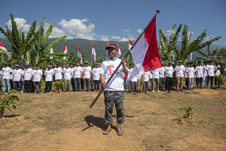 Seorang mantan narapidana terorisme mengibarkan bendera merah putih seusai mengikuti kegiatan pembentangan bendera merah putih di kaki Gunung Biru, Desa Pantangolemba, Kecamatan Poso Pesisir Selatan, Poso, Sulawesi Tengah, Jumat, 16 Agustus 2024. [Taufan Bustan/BenarNews]