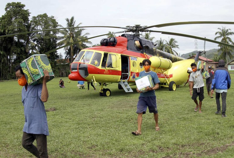 Warga korban gempa membantu mengangkat bantuan logistik yang dikeluarkan dari sebuah helikopter di Majene, Sulawesi Barat, 20 Januari 2021. [AP]
