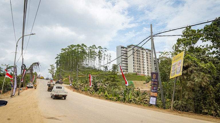 Bendera Merah-Putih dan umbul-umbul tampak sepanjang jalan negara menyambut hari kemerdekaan Indonesia, dengan latar rumah susun aparatur sipil negara ASN di IKN, Desa Bumi Harapan, Sepaku, Penajam Paser Utara, 12 Agustus 2024. [Muhibar Sobary Ardan/BenarNews]