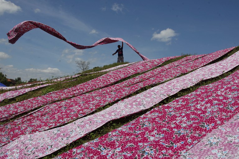 Seorang pekerja menjemur kain batik di kawasan industri di Sukoharjo, Jawa Tengah, 15 Juli 2021. [Antara Foto/Maulana Surya/via Reuters]