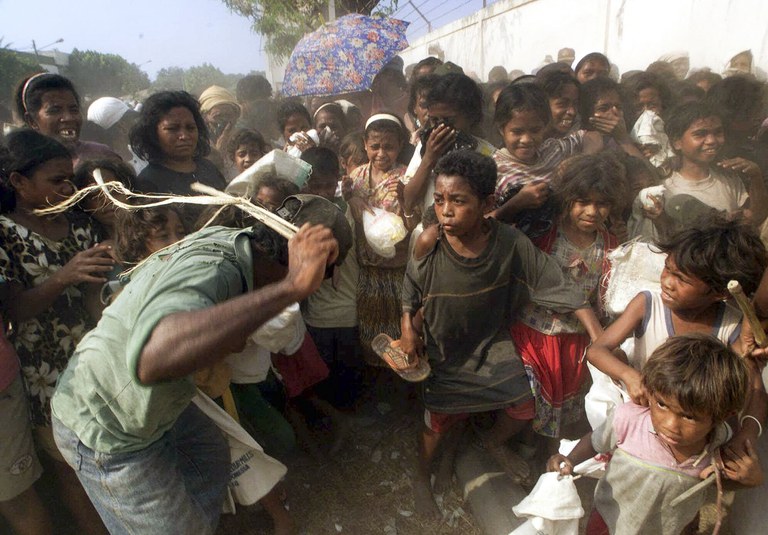Dalam foto 20 Oktober 1999 ini, di masa krisis kemanusiaan yang menyusul setelah kekerasan pasca pemungutan suara yang disponsori PBB, warga yang sedang dalam antrean panjang menunggu jatah beras harian di Dili, Timor Timur, didorong mundur. [Charles Dharapak/AP]