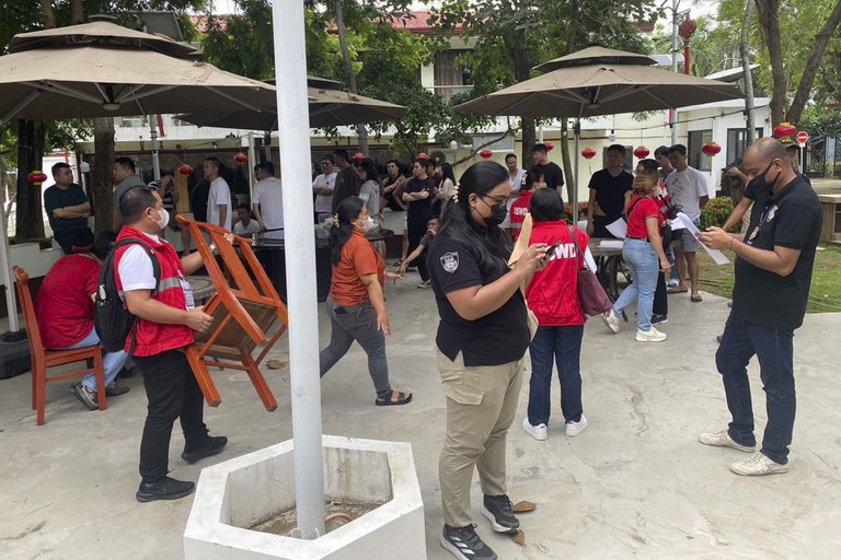 Dalam foto yang disediakan oleh Biro Imigrasi Filipina ini, para petugas, mengenakan jaket merah dan kemeja hitam memantau aktivitas saat penggerebekan di kompleks yang diduga sebagai tempat perjudian daring ilegal dan penipuan siber di kota Lapu-Lapu, provinsi Cebu, Filipina, 31 Agustus 2024. [Biro Imigrasi Filipina via AP]