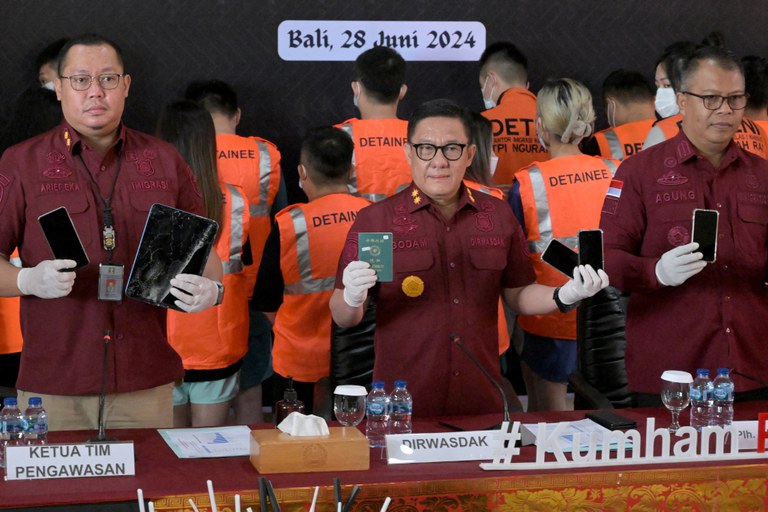 Pejabat imigrasi Indonesia memperlihatkan barang bukti paspor dan telepon genggam yang disita dari warga Taiwan yang ditangkap karena penipuan siber dalam konferensi pers di Rumah Detensi Imigrasi Denpasar, di Kabupaten Badung, Bali, pada 28 Juni 2024. [Sonny Tumbelaka/AFP]