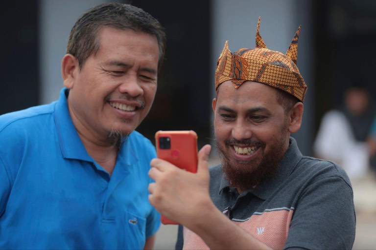 Militan JI Umar Patek (kanan) menggunakan ponselnya untuk melakukan panggilan video saat bertemu dengan teman lamanya Ali Fauzi, mantan pembuat bom yang menjalankan program untuk menderadikalisasi militan, di Lamongan, Jawa Timur, 13 Desember 2022. [Trisnadi/AP]