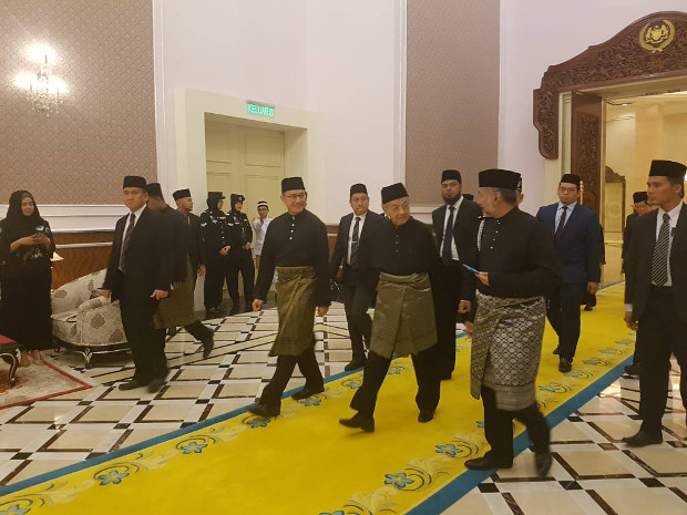 Pengerusi Pakatan Harapan Mahathir Mohamad (tiga dari kiri), berbual dengan anak lelakinya, Mokhzani, ketika berjalan ke balai istiadat di istana negara untuk upacara angkat sumpah beliau sebagai perdana menteri Malaysia yang baharu, 10 Mei 2018.  [S. Mahfuz/BeritaBenar]