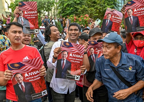 Penyokong Anwar Ibrahim mengangkat posternya ketika berkumpul di luar pekarangan Istana Negara, Kuala Lumpur, 22 November 2022.
