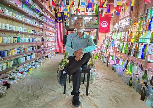 Tengku Mohd Ali Tengku Mansor duduk di tengah-tengah ribuan koleksi botol ditemui di tepi pantai yang ditempatkan di Rumah Botol, Kampung Penarik, Setiu, Terengganu, 16 November 2024.