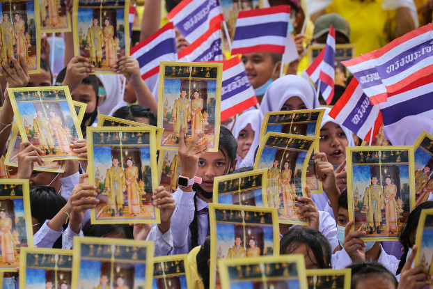 นักเรียนชูพระบรมฉายาลักษณ์ของพระบาทสมเด็จพระเจ้าอยู่หัว และสมเด็จพระนางเจ้าฯ พระบรมราชินี พร้อมโบกธงชาติไทย ขณะร่วมกิจกรรม "รวมพลคนปัตตานี ปกป้องสถาบันชาติ ศาสนา พระมหากษัตริย์" หน้าศาลากลางจังหวัดปัตตานี วันที่ 22 ตุลาคม 2563 (เอเอฟพี)