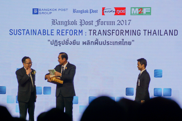 พล.อ.ประยุทธ์ จันทร์โอชา นายกรัฐมนตรี รับของที่ระลึกจากนายสุทธิเกียรติ จิราธิวัฒน์ เจ้าของหนังสือพิมพ์บางกอกโพสต์ หลังจากการปาฐกถาในงาน “บางกอกโพสต์ฟอรั่ม 2560” วันที่ 24 สิงหาคม 2560 (ภิมุข รักขนาม/เบนาร์นิวส์)